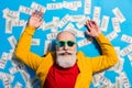 High angle view photo of positive good mood mature man lying floor with money isolated on blue color background Royalty Free Stock Photo