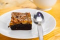 High angle view of a piece of delicious homemade toffee cake and metal spoon in white ceramic dish