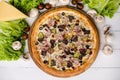 High angle view of pizza on wooden table surrounded by mushrooms and cheese Royalty Free Stock Photo