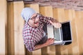 High angle view portrait of fashionable freelancer blogger sitting on stairs and showing thumbs up while holding laptop Royalty Free Stock Photo