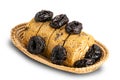 High angle view of prune sponge cake roll and dried pitted prune in bamboo basket on white background