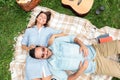 High angle view of romantic young couple lying on their backs on a picnic blanket, cuddling