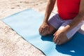 High angle view of senior biracial man kneeling on yoga mat at sunny beach