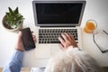 High angle view of a senior man`s hands  writing on the computer and using the cellphone. Laptop and wireless technology. White Royalty Free Stock Photo