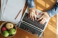 High-angle view shows a woman`s hands are typing on laptop . which has papers and fruits put on the table at the The sun shines Royalty Free Stock Photo