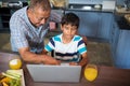 High angle view of smiling grandfather assisting grandson using laptop Royalty Free Stock Photo