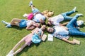 high angle view of smiling teenage classmates with books and backpacks lying together