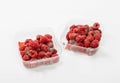 High-angle view of spoilt raspberries in plastic clamshell containers on a white background