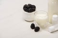 High angle view of sugar bowl with blackberries, bottle and glass of yogurt near containers with starter cultures