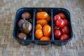 Tomato Varieties ,Type and color mixed together in black plastic basket on wooden floor Royalty Free Stock Photo