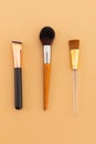 High angle view of three makeup brushes on yellow background