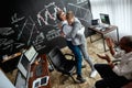 High-angle view of three traders celebrating their success while working in the office. Blackboard full of charts and