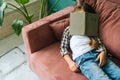 High-angle view of tired sleepy child kid girl lying on soft couch with paper book on head at home. Royalty Free Stock Photo