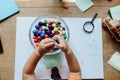 High angle view of a toddler holding beads over a bowl