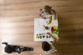 Children painting on table with dog lying on floor