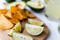 Fresh avocado, lime, drink and nacho chips lying on marble background. Recipe for Cinco de Mayo party Royalty Free Stock Photo