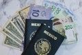 High angle view of two Mexican Passports on dollars and pesos on the table under the lights