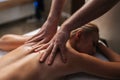 High-angle view of unrecognizable male masseur doing back and neck massage to naked female client in spa salon lying on Royalty Free Stock Photo