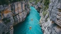 High angle view of unrecognizable people kayaking on blue narrow river flowing between rocky mountains during vacation at daytime