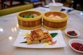 High angle view of a variety of traditional dim sum dishes on dining table in restaurant. Dumplings in bamboo steamer baskets, and