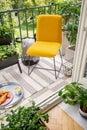 Vibrant yellow chair and home plants on a peaceful balcony with string lights, sweet breakfast and a striped