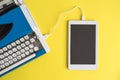 High angle view of vintage typewriter connected with digital tablet on yellow Royalty Free Stock Photo