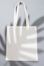 High angle view of white canvas bag with copy space and leaf shadow on grey background Royalty Free Stock Photo