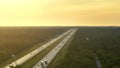 High angle view of wide congested american highway with many driving cars and trucks at sunset. Concept of interstate