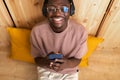 High angle view of young black man Listening to music with wireless headphones using mobile phone at home. Royalty Free Stock Photo