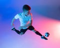 High angle view of young man, male soccer football player training isolated on gradient blue pink background in neon Royalty Free Stock Photo