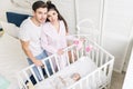 High angle view of young parents standing at crib with little baby