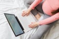 High angle view of young pregnant woman sitting on bed and using laptop Royalty Free Stock Photo