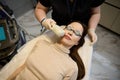 Top view of a young pretty woman wearing UV protective goggles, receiving facial laser treatment and lying down on the daybed in a Royalty Free Stock Photo