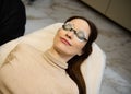 Top view of a young pretty woman wearing UV protective goggles and lying down on the daybed in a wellness spa clinic Royalty Free Stock Photo