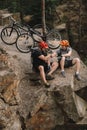 high angle view of young trial bikers relaxing on rocky cliff after ride and shaking