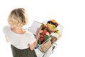 high angle view of young woman holding blank notebook and shopping trolley with grocery bags