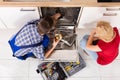 Woman Looking At Repairman Repairing Dishwasher Royalty Free Stock Photo