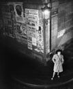 High angle view of a young woman waiting next to a lantern on a dark street corner