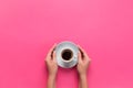 High angle of woman hands holding coffee cup on pink background Minimalistic style. Flat lay, top view isolated
