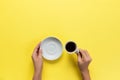 High angle of woman hands holding coffee cup on yellow background Minimalistic style. Flat lay, top view isolated