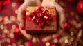 High angle of woman hands holding diagonally gift box wrapped with red ribbon over red background Royalty Free Stock Photo
