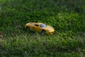 High angle zoomed close up shot of one yellow toy car on grass in the garden during sunrise and light rays falling on it