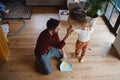 High anlge view of father high fiving with small son after sweeping at home, daily chores concept. Royalty Free Stock Photo