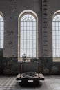 High arcade window in an old factory. Rusted, industrial space, dirty walls and historical floor tiles. Old, metal cart with an