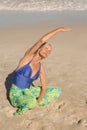 High bangle view of woman exercising while sitting on sand Royalty Free Stock Photo