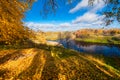 High bank of the river with trees, leaves on the ground and fishermen in the boats on the river Royalty Free Stock Photo