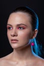 High beauty photo of sexy young girl with blue eyes, round pink earrings and wonderful professional makeup