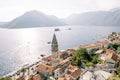 High bell tower among the red roofs of ancient houses on the shore of the Bay of Kotor. Perast, Montenegro. Drone