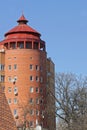 high brown brick tower high-rise building with windows under a red tiled roof Royalty Free Stock Photo
