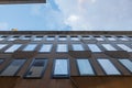 High building facade forced ground perspective on a narrow street with a cloudy sky